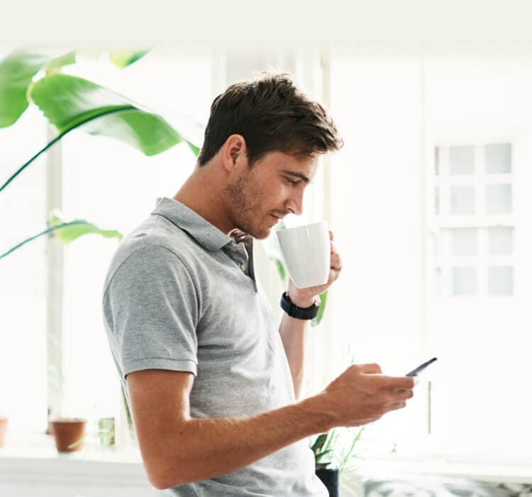 Man die koffie drinkt terwijl hij een mobiele telefoon vasthoudt