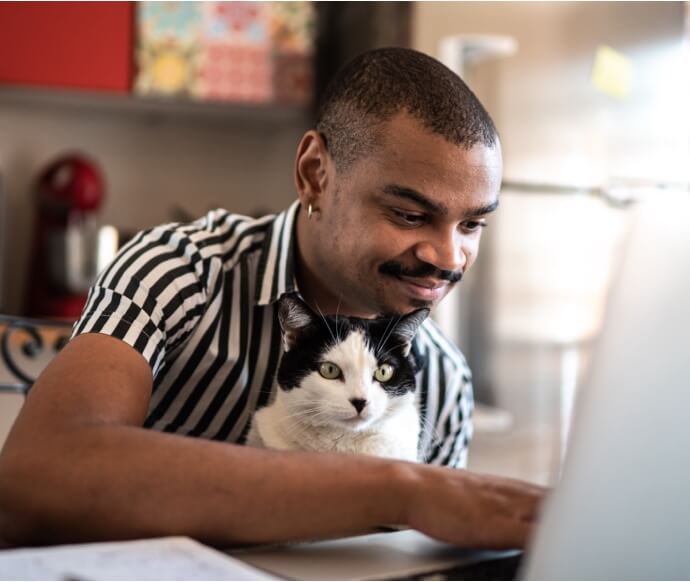 Man met kat die op een laptop werkt