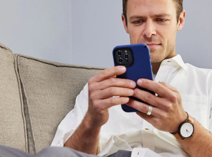 Man op bank kijkt naar telefoon