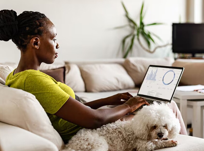 Zittende vrouw met hond die op laptop werkt