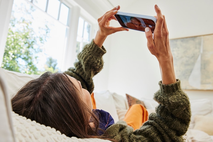 Vrouw die ligt te kijken naar een mobiele telefoon